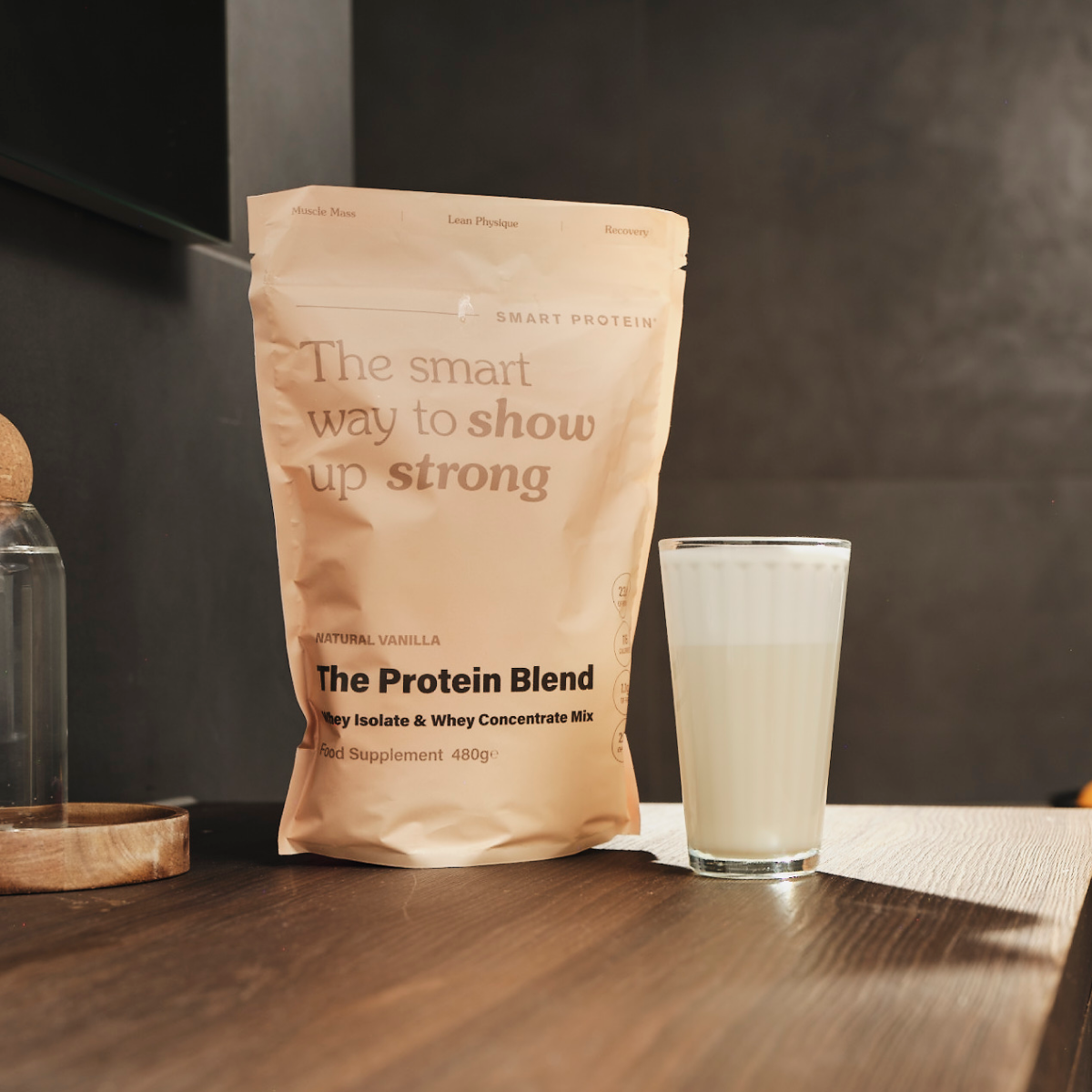 Whey Isolate Protein Blend by Smart Protein on the counter next to a glass